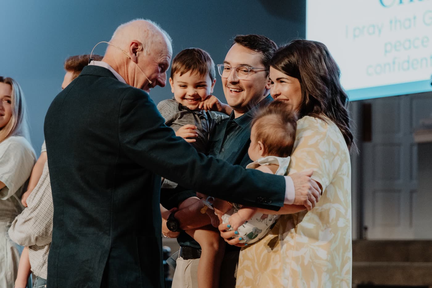 David McKinley laughing as he embraces a young father holding his two children on the Warren platform