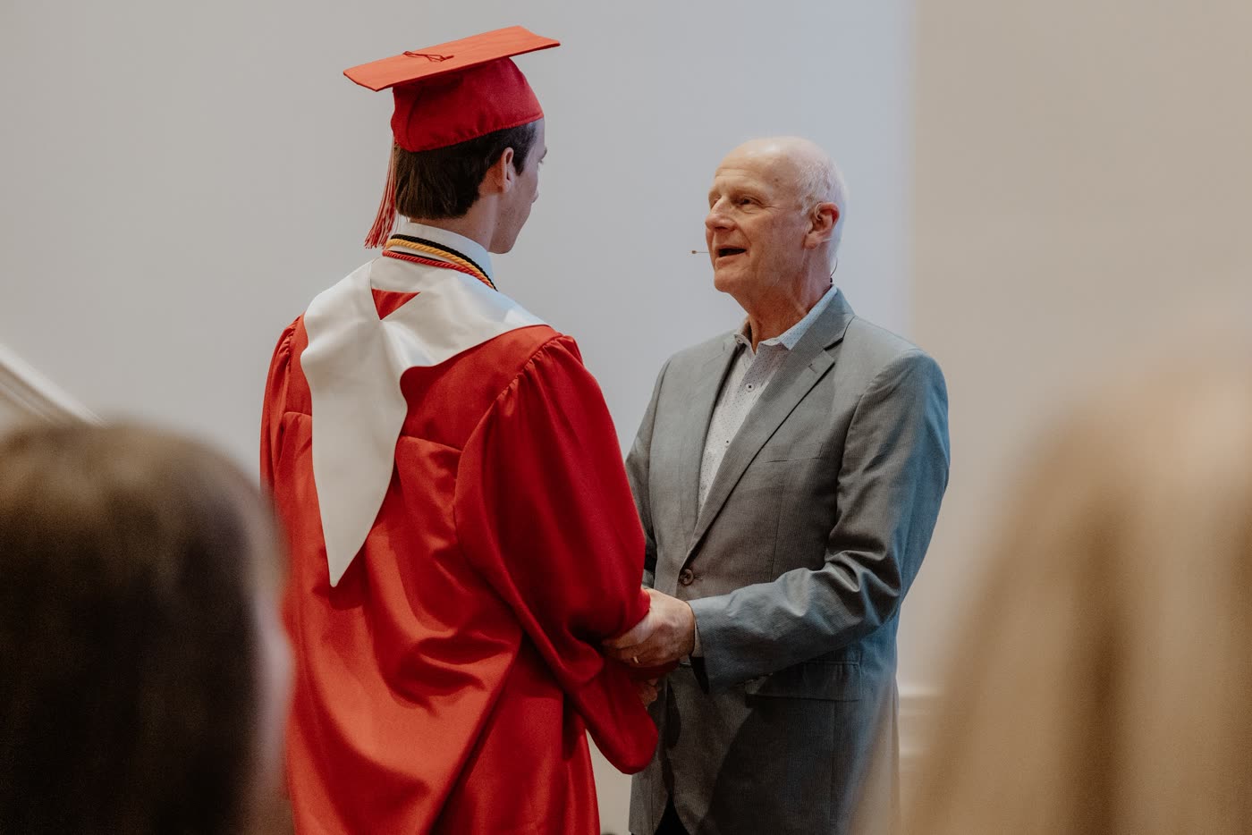 David McKinley congratulating a graduate wearing a red gown