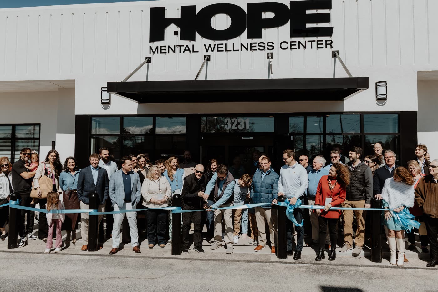 A crowd cutting the ribbon at the entrance of the Hope Mental Wellness Center