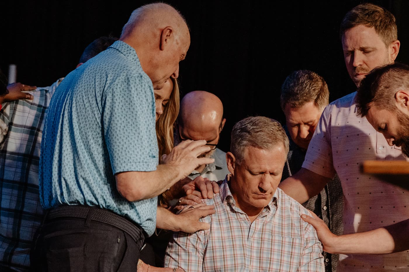 David McKinley laying a hand on a man in prayer, surrounded by others praying